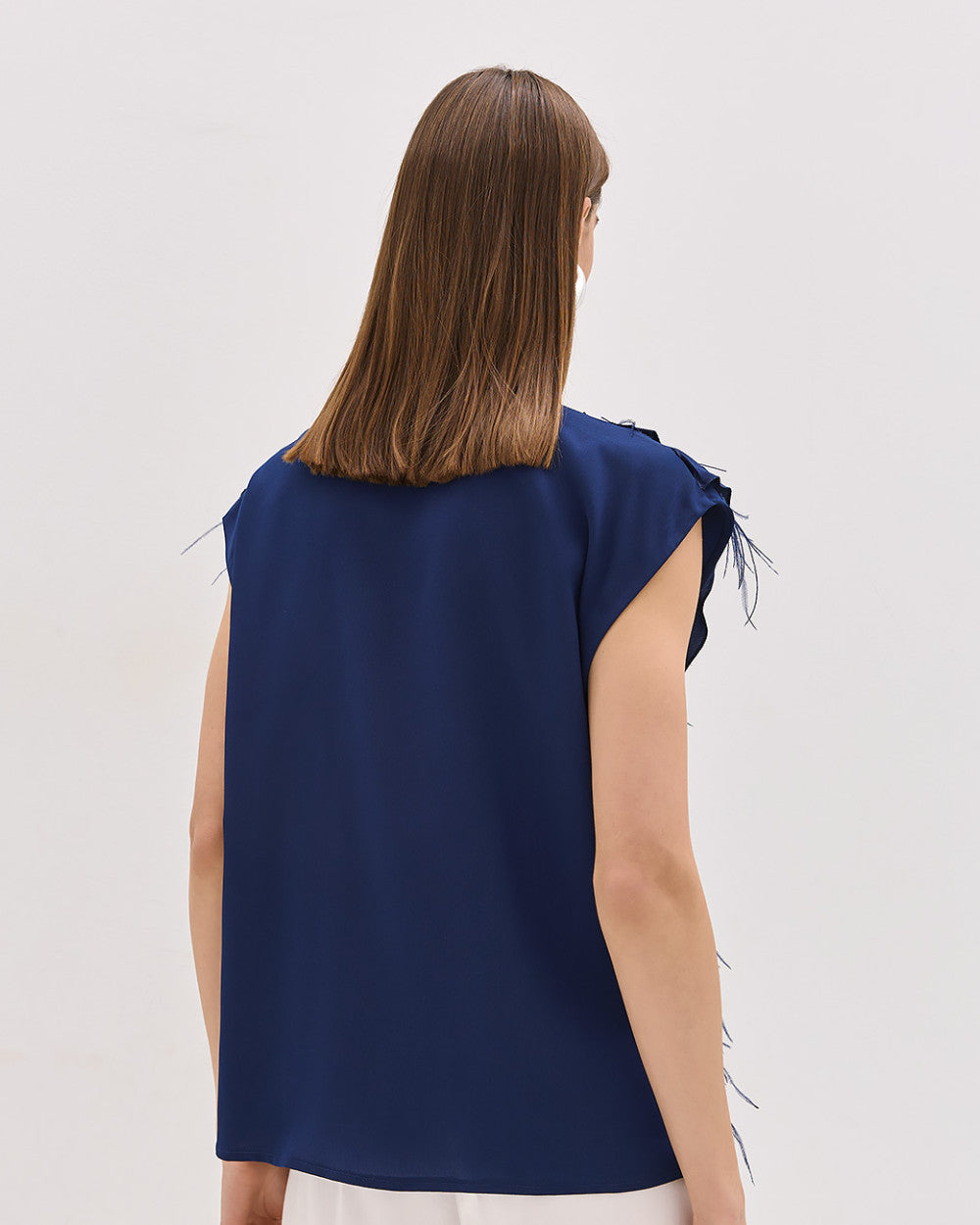 Camicia blu senza maniche con volant e piume